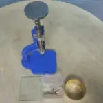 Glass bottle cutter machine with adjustable stand, cutting tools, and circular glass samples for laboratory and workshop use.