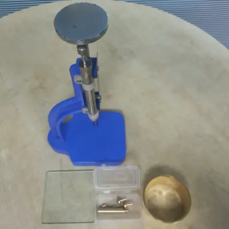 Glass bottle cutter machine with adjustable stand, cutting tools, and circular glass samples for laboratory and workshop use.