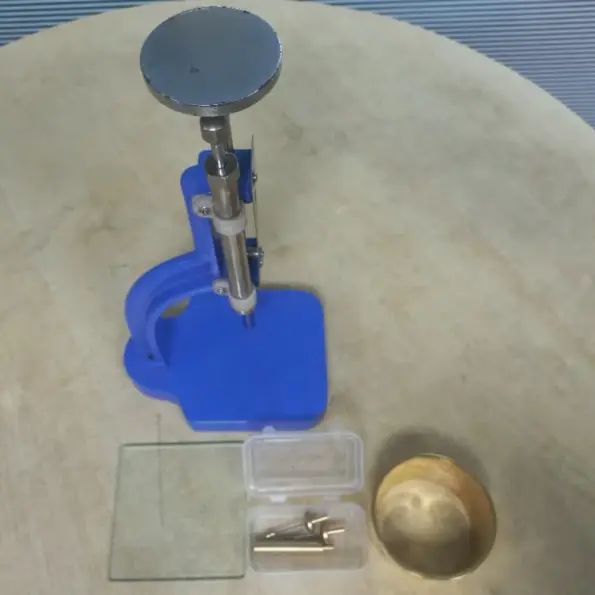 Glass bottle cutter machine with adjustable stand, cutting tools, and circular glass samples for laboratory and workshop use.