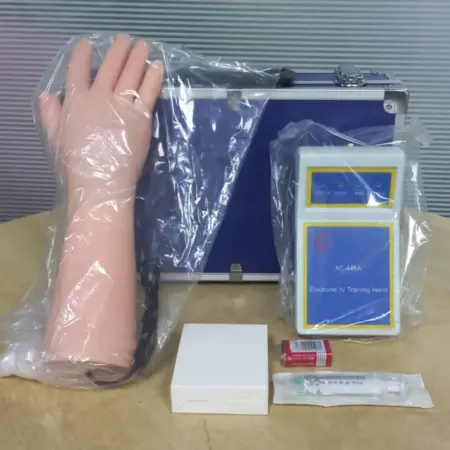 Electronic IV training hand kit with lifelike arm model, control unit, tubing, and accessories for nursing venipuncture and injection practice.
